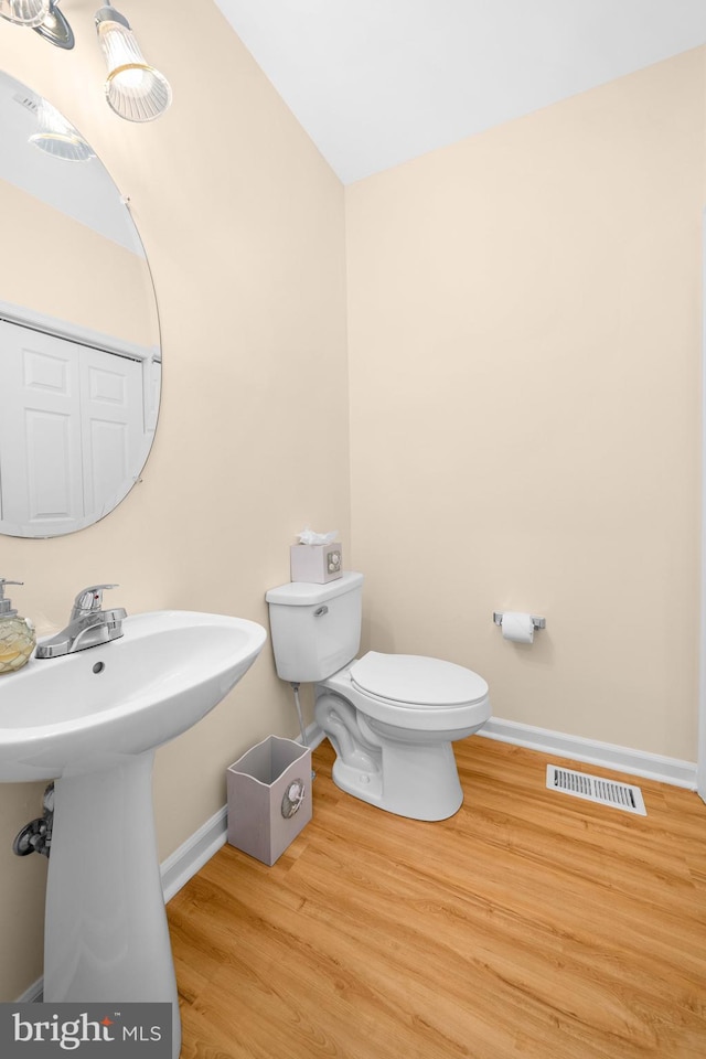 bathroom featuring wood-type flooring, toilet, and sink