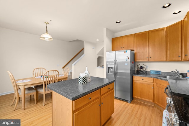 kitchen with sink, stainless steel appliances, light hardwood / wood-style floors, decorative light fixtures, and a kitchen island