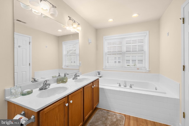 bathroom featuring vanity, tiled bath, and hardwood / wood-style flooring