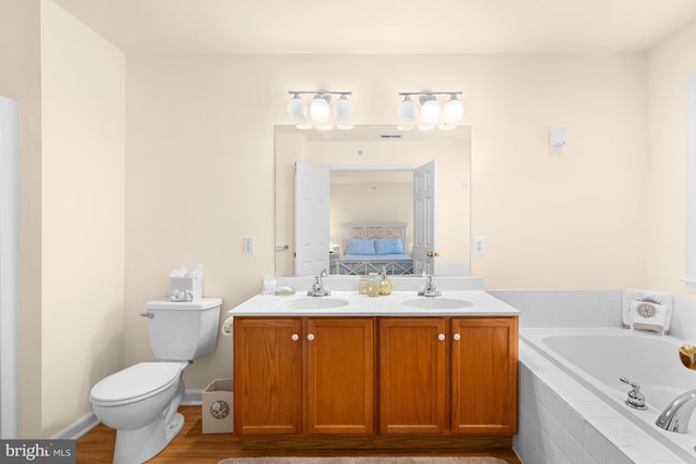 bathroom featuring tiled tub, toilet, vanity, and hardwood / wood-style flooring