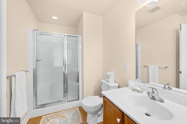 bathroom featuring toilet, vanity, a shower with door, and hardwood / wood-style flooring