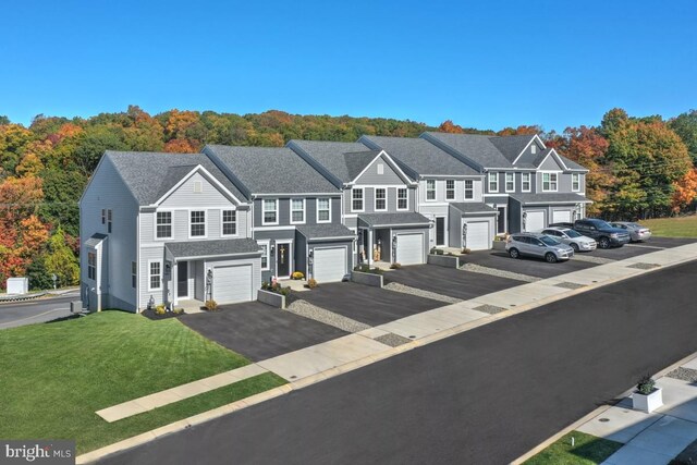 townhome / multi-family property featuring a garage and a front lawn