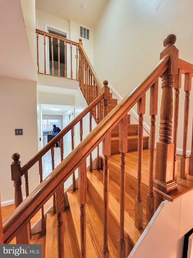 staircase with hardwood / wood-style floors and a towering ceiling