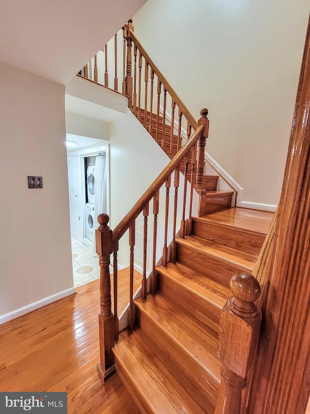 staircase with hardwood / wood-style flooring and stacked washer / dryer