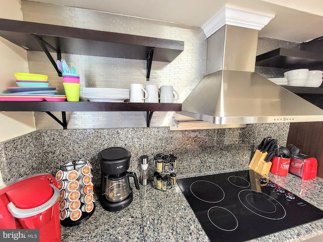 kitchen featuring backsplash, island exhaust hood, light stone counters, and black electric cooktop