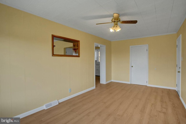 empty room featuring light wood-type flooring, ceiling fan, and crown molding