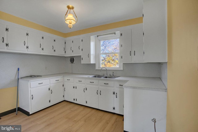 kitchen featuring white cabinets, light wood-type flooring, sink, and tasteful backsplash