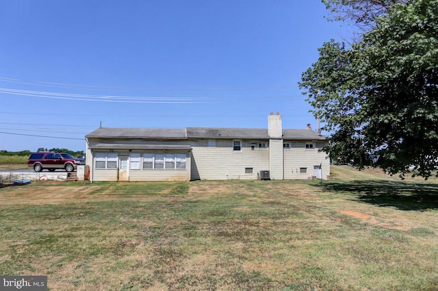 back of property with a yard and central AC