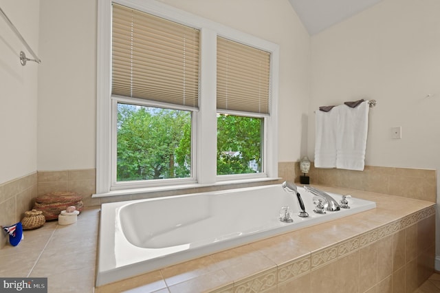 bathroom featuring a relaxing tiled tub and lofted ceiling