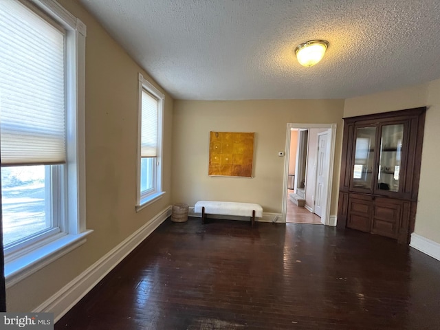 unfurnished room with plenty of natural light, dark hardwood / wood-style floors, and a textured ceiling