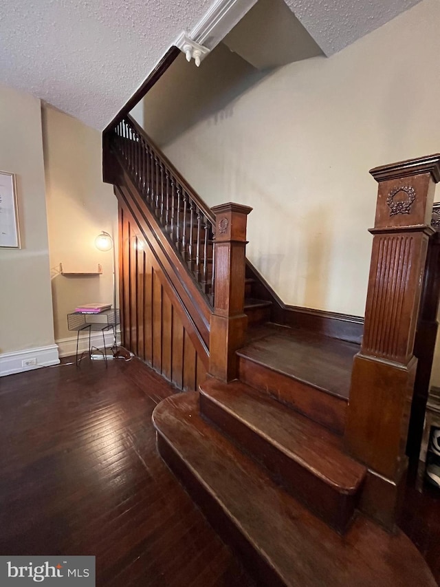 stairway with hardwood / wood-style floors and a textured ceiling