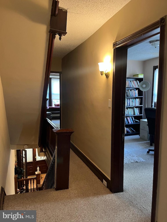 corridor featuring light carpet and a textured ceiling