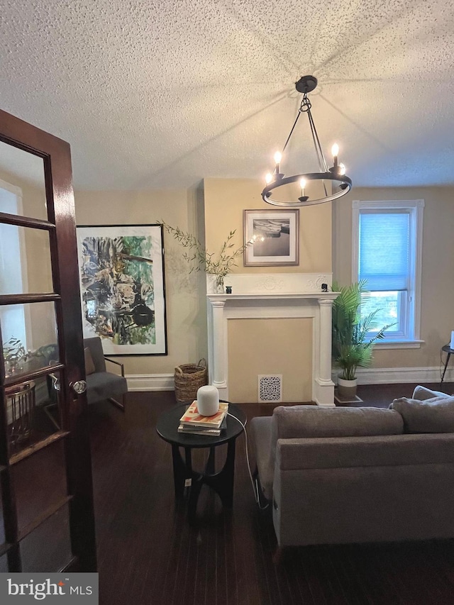 living room with a textured ceiling, hardwood / wood-style flooring, and an inviting chandelier