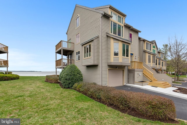 view of side of home featuring a yard, a water view, and a garage