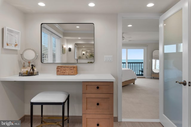 interior space featuring ornamental molding, vanity, ceiling fan, wood-type flooring, and a water view