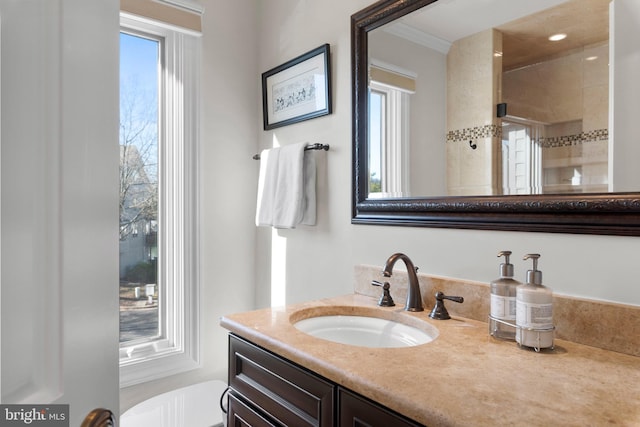 bathroom featuring tiled shower, vanity, and ornamental molding