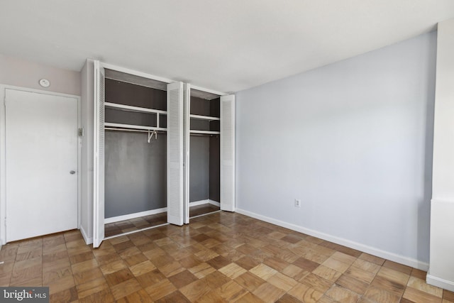 unfurnished bedroom featuring parquet flooring and a closet