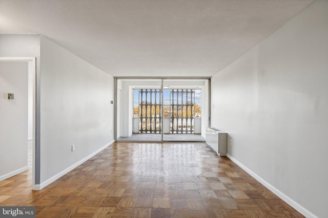 unfurnished room featuring parquet flooring, a textured ceiling, and radiator