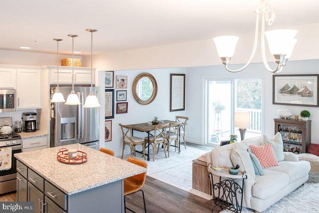 kitchen featuring hanging light fixtures, stainless steel appliances, a chandelier, wood-type flooring, and white cabinets