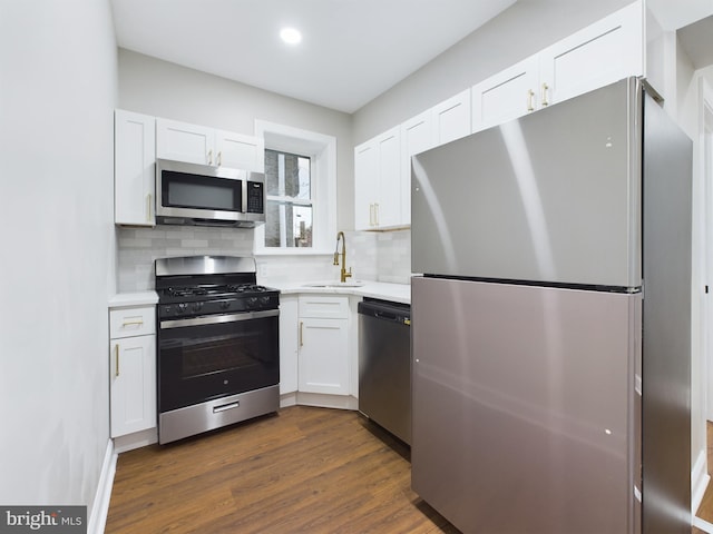 kitchen with decorative backsplash, appliances with stainless steel finishes, sink, white cabinets, and dark hardwood / wood-style floors