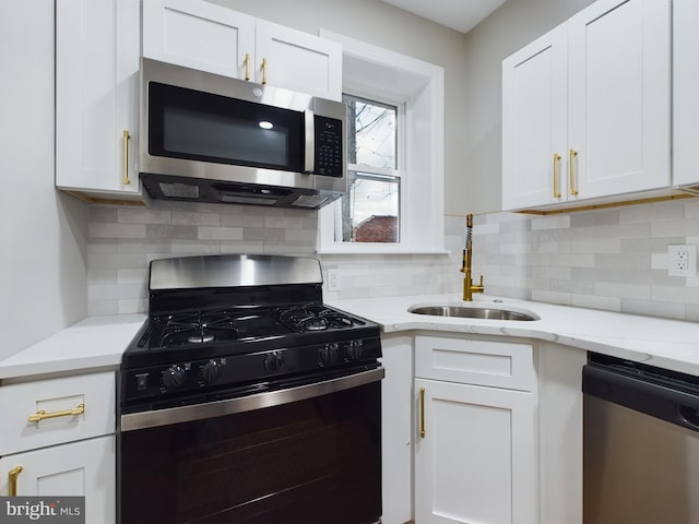 kitchen with tasteful backsplash, sink, white cabinets, and appliances with stainless steel finishes