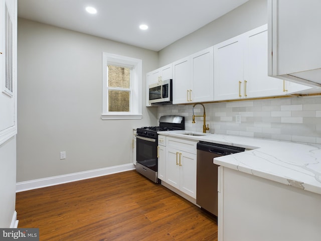 kitchen with appliances with stainless steel finishes, dark hardwood / wood-style flooring, light stone counters, sink, and white cabinetry