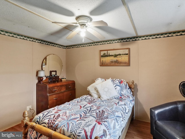 bedroom with hardwood / wood-style floors, a textured ceiling, and ceiling fan