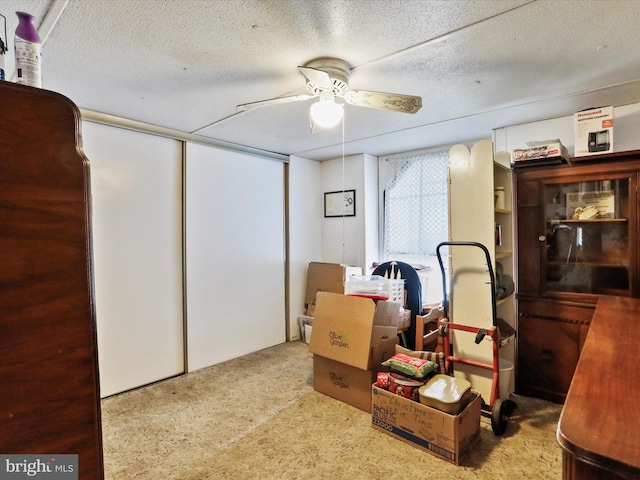 basement with carpet flooring, ceiling fan, and a textured ceiling