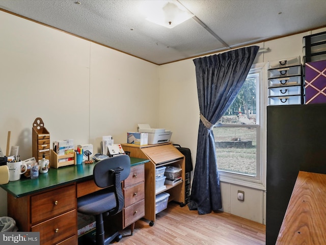 home office with light hardwood / wood-style floors and a textured ceiling