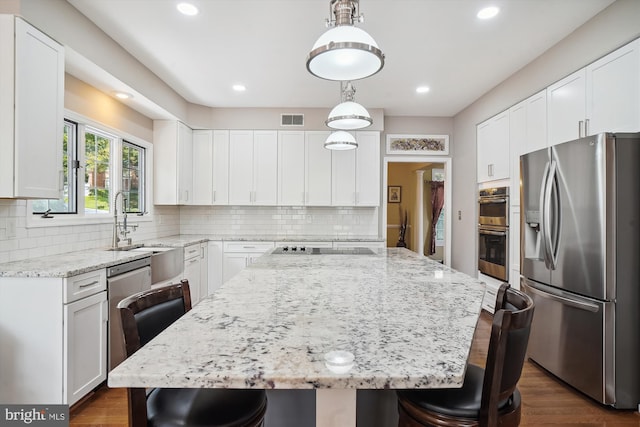 kitchen with visible vents, stainless steel appliances, light stone counters, and a kitchen breakfast bar