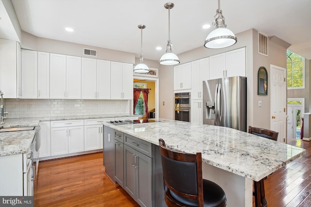 kitchen with appliances with stainless steel finishes, a breakfast bar, gray cabinets, and decorative backsplash