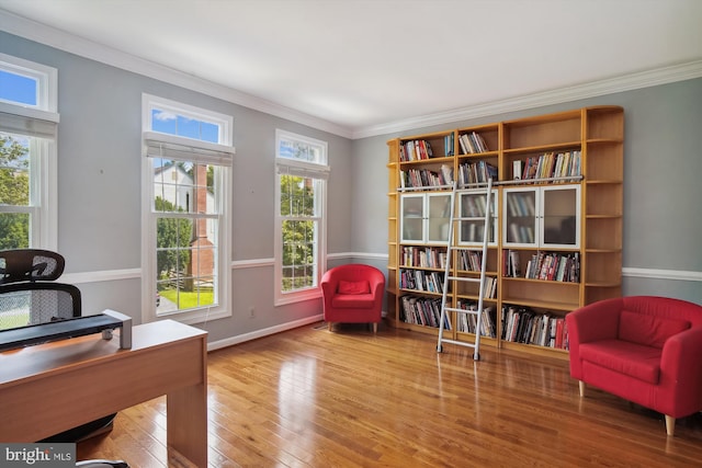 living area with plenty of natural light, wood-type flooring, baseboards, and crown molding