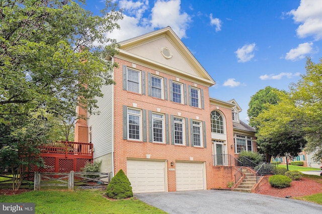 greek revival house featuring aphalt driveway, an attached garage, fence, and brick siding