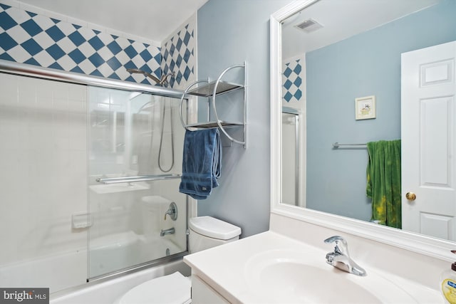 bathroom with toilet, visible vents, bath / shower combo with glass door, and vanity