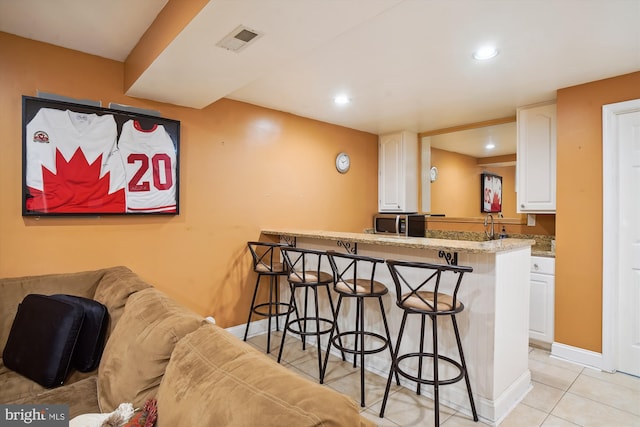 bar with light tile patterned floors, recessed lighting, visible vents, stainless steel microwave, and baseboards