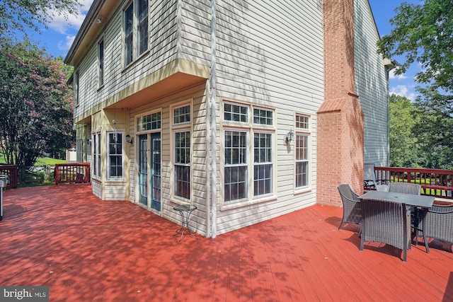 view of side of property featuring a chimney, outdoor dining area, and a wooden deck