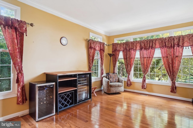 living area with hardwood / wood-style floors, beverage cooler, and crown molding