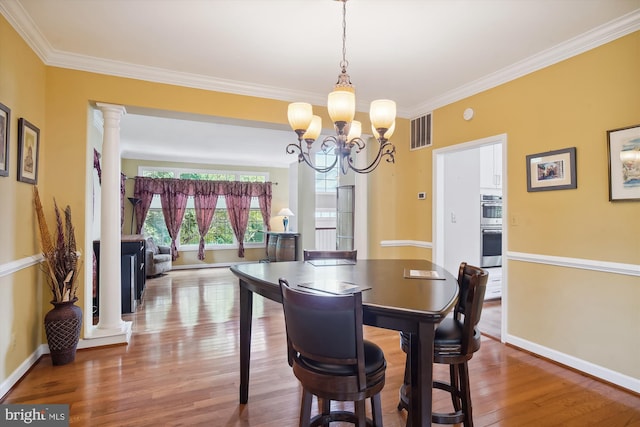 dining area with baseboards, visible vents, wood finished floors, ornate columns, and a chandelier