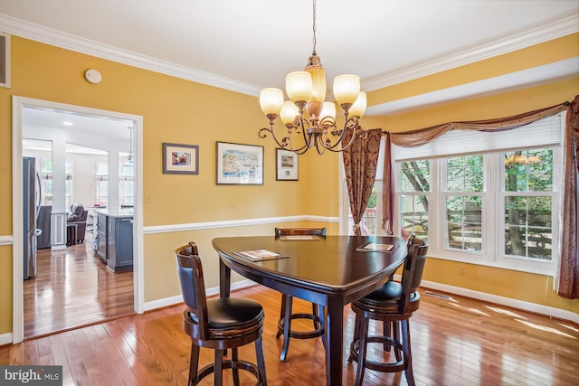 dining room featuring ornamental molding, hardwood / wood-style floors, and a chandelier