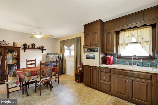 kitchen featuring oven, a healthy amount of sunlight, sink, and ceiling fan