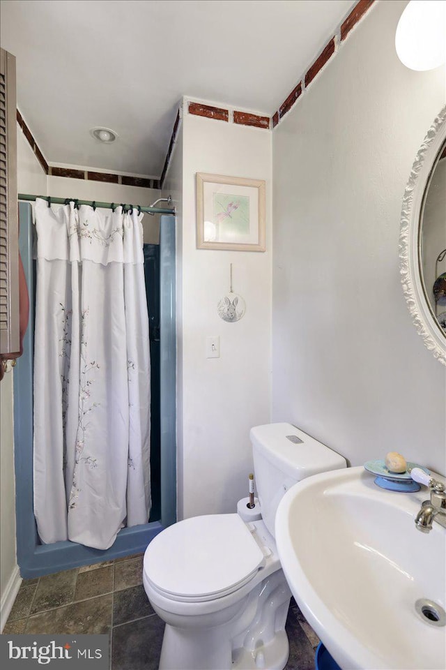 bathroom featuring a shower with curtain, toilet, and sink