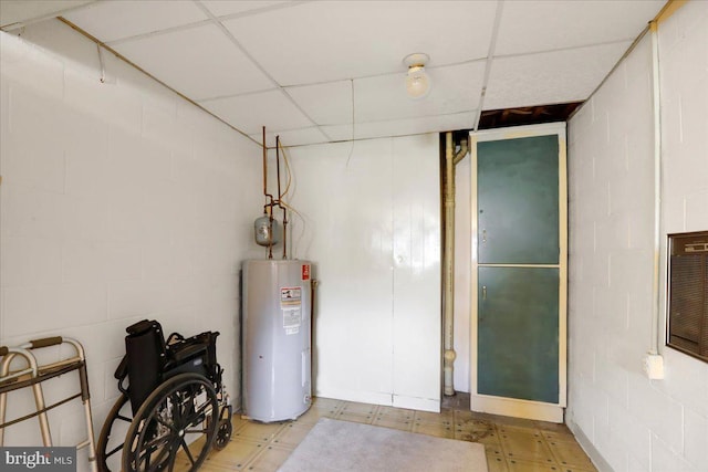 basement featuring electric water heater and a drop ceiling