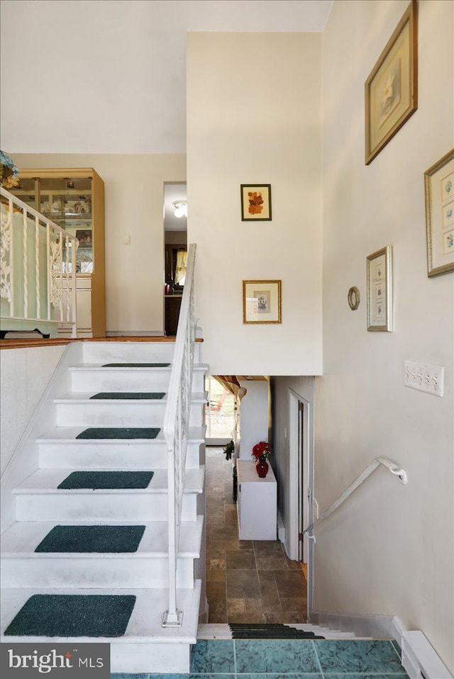 staircase featuring a baseboard heating unit