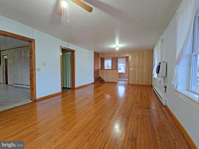 unfurnished room with hardwood / wood-style floors, a wealth of natural light, and a baseboard heating unit