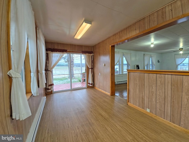 spare room with wood walls, ceiling fan, light hardwood / wood-style floors, and a baseboard radiator