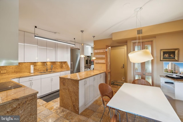 kitchen featuring a center island, sink, stainless steel fridge, decorative light fixtures, and white cabinets