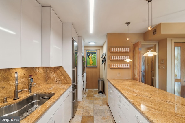 kitchen with white cabinetry, sink, light stone counters, and decorative light fixtures