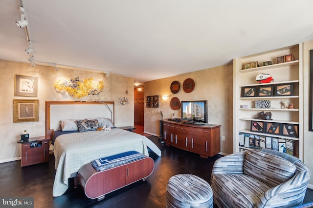 bedroom with dark hardwood / wood-style flooring and rail lighting