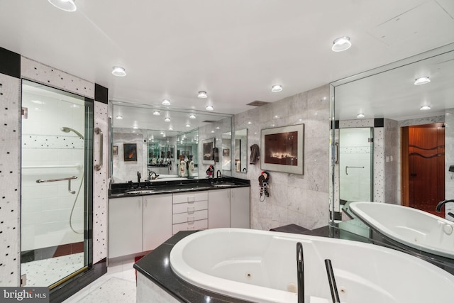 bathroom featuring plus walk in shower, vanity, and tile walls