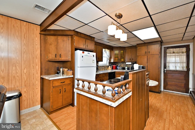 kitchen featuring wooden walls, light hardwood / wood-style flooring, and decorative light fixtures